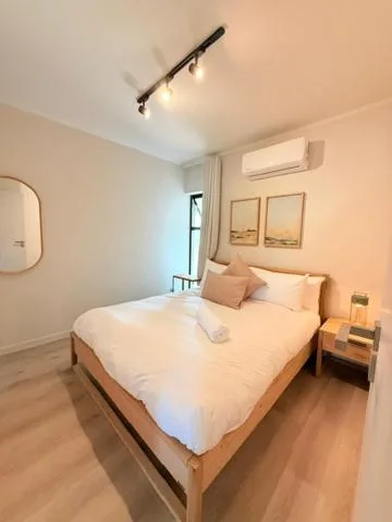 Bright bedroom with queen bed, wooden frame, bedside table, and mirror