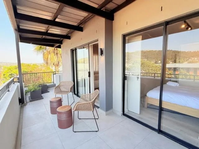 Spacious covered balcony with seating overlooking lush green hills and valley