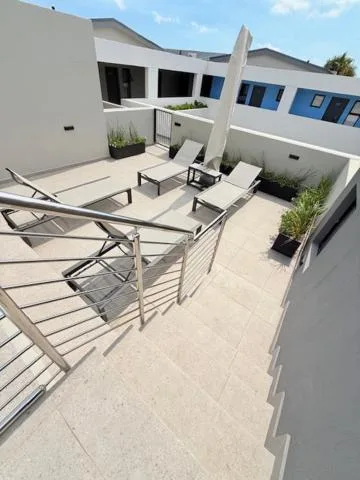 Spacious paved outdoor deck with loungers, umbrella, and modern railing