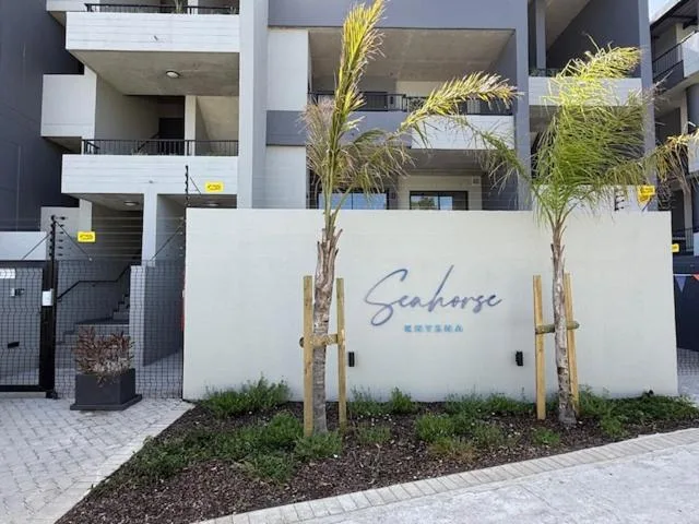 Modern apartment building entrance with Seahorse branding and palm landscaping