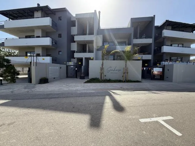 Modern apartment building facade with white walls and dark accents, gated entrance