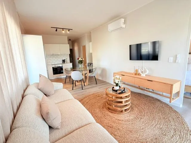 Open-plan living area with cream sofa, wooden furniture, and mounted TV
