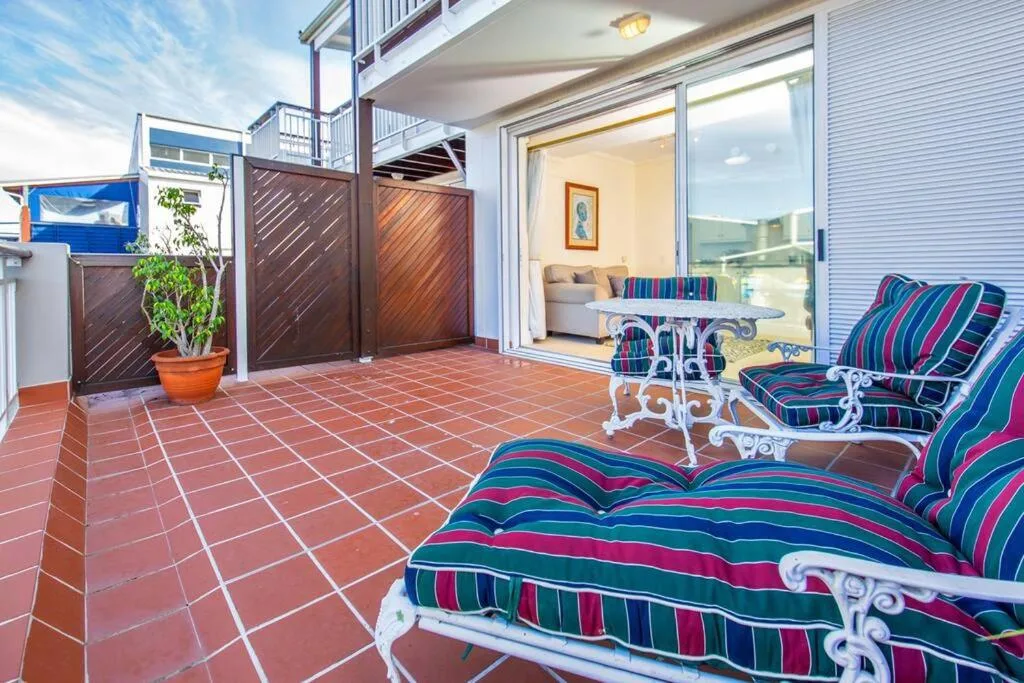 Spacious terracotta tiled patio with colorful loungers and ocean views