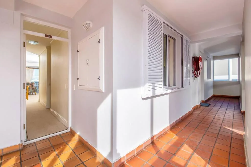 Bright hallway with terracotta tiles and white walls, leading to rooms