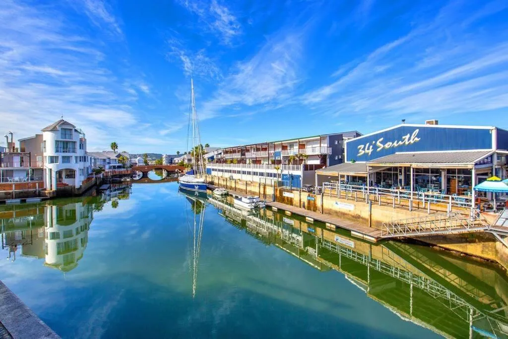 Knysna Heads waterfront with boats, colorful buildings, and clear blue sky
