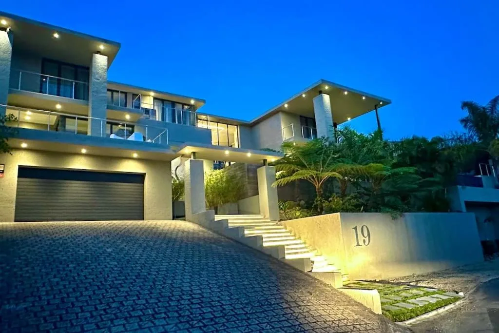 Modern villa facade with illuminated driveway and numbered entrance at dusk