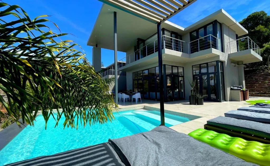 Modern villa with sparkling pool, lounge seating, and tropical landscaping