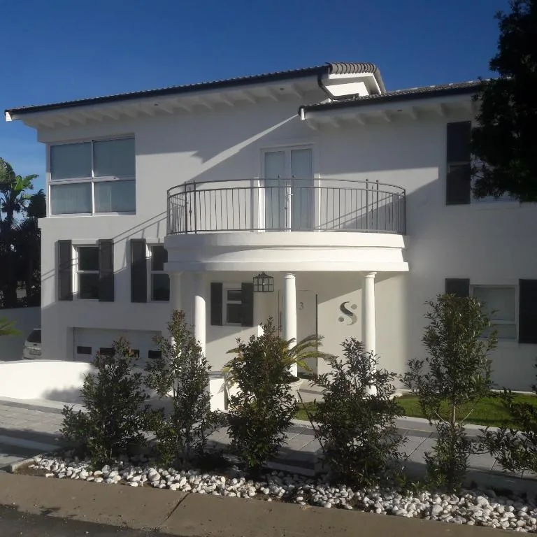 Modern white two-story house with curved balcony and manicured landscaping