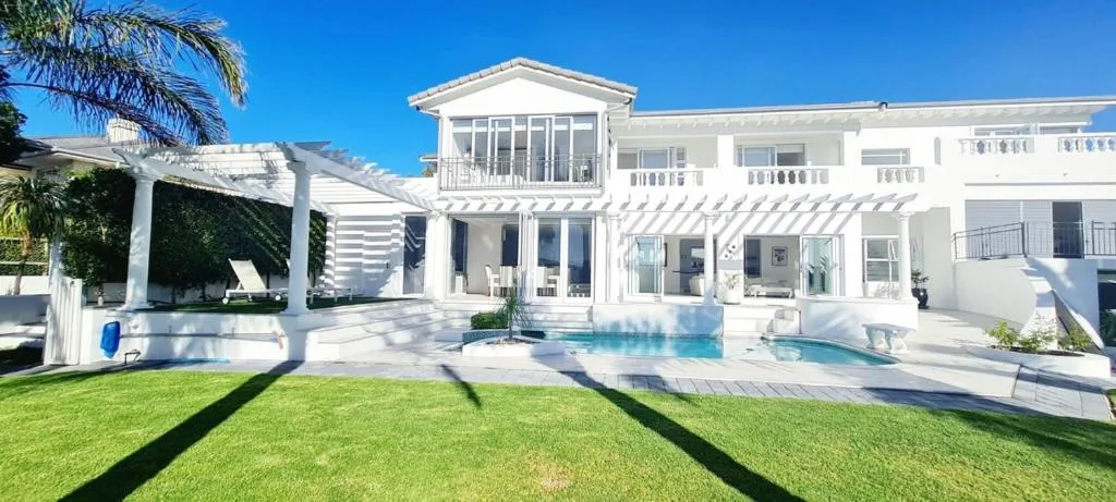 Modern white beachfront villa with pool and manicured lawn garden area