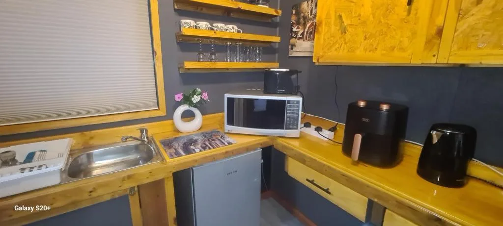 Bright yellow kitchen with counters, microwave, appliances and open shelving