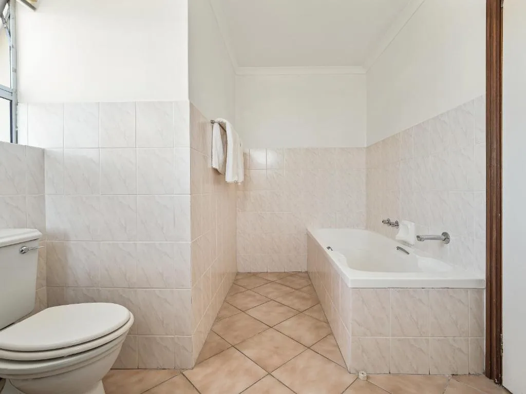 Clean bathroom with toilet, bathtub, tiled walls, and towel rail