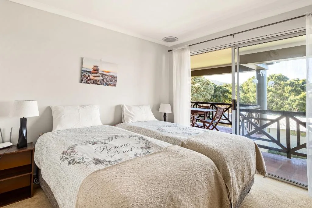 Bright bedroom with twin beds and garden view through glass doors