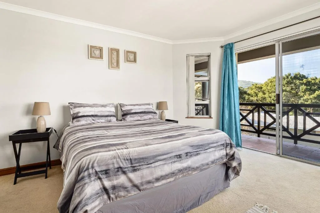 Bright bedroom with queen bed, striped bedding, and sliding doors to garden view