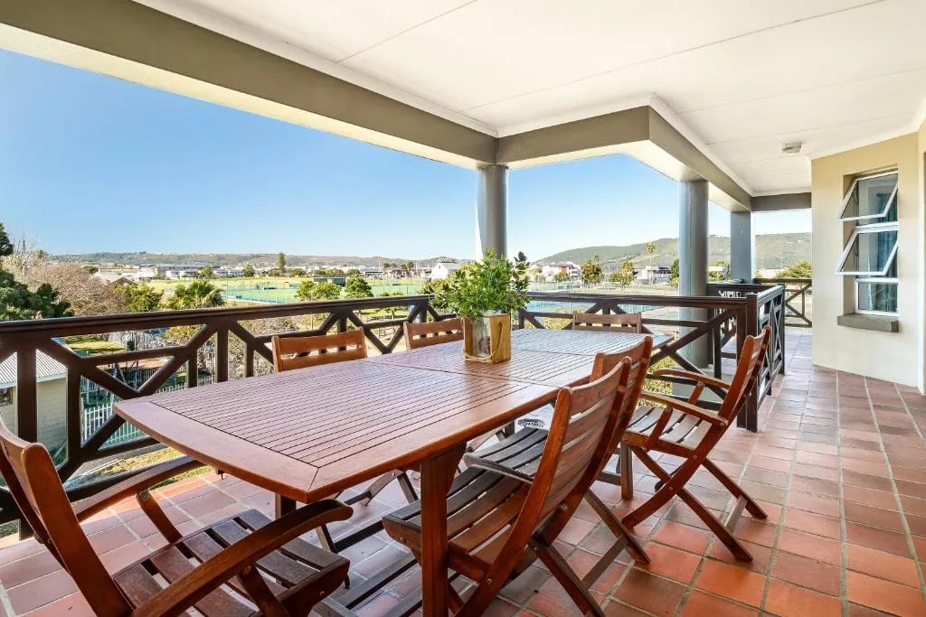 Covered terrace with wooden dining table overlooking Knysna lagoon and hills