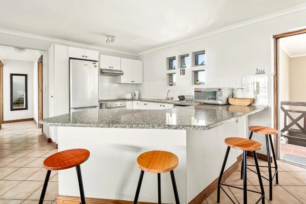 Modern kitchen with white cabinetry, granite countertop, and wooden bar stools