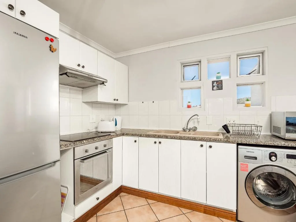 Bright white kitchen with granite countertops, modern appliances, and windows