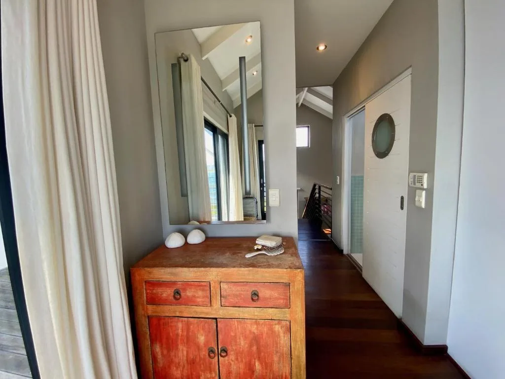 Modern bathroom with wooden vanity, large mirror, and skylight overhead