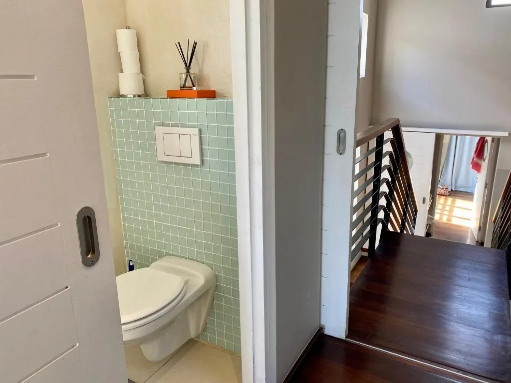 Compact bathroom with mint green tile walls and modern white toilet