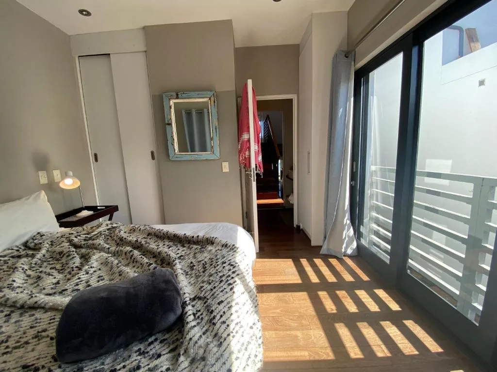 Bright bedroom with queen bed, coastal mirror, and sliding glass doors opening to deck