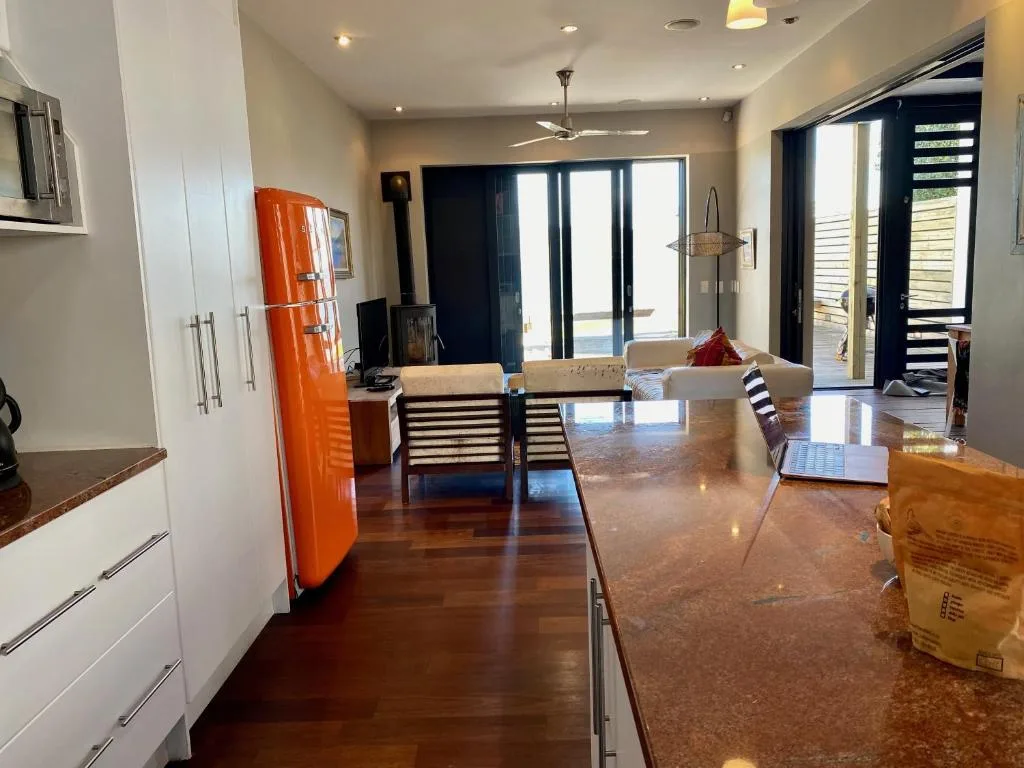 Open-plan kitchen with orange retro fridge and modern countertops