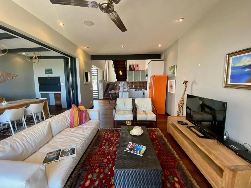 Spacious open-plan lounge with cream sofa, TV, and dining area beyond