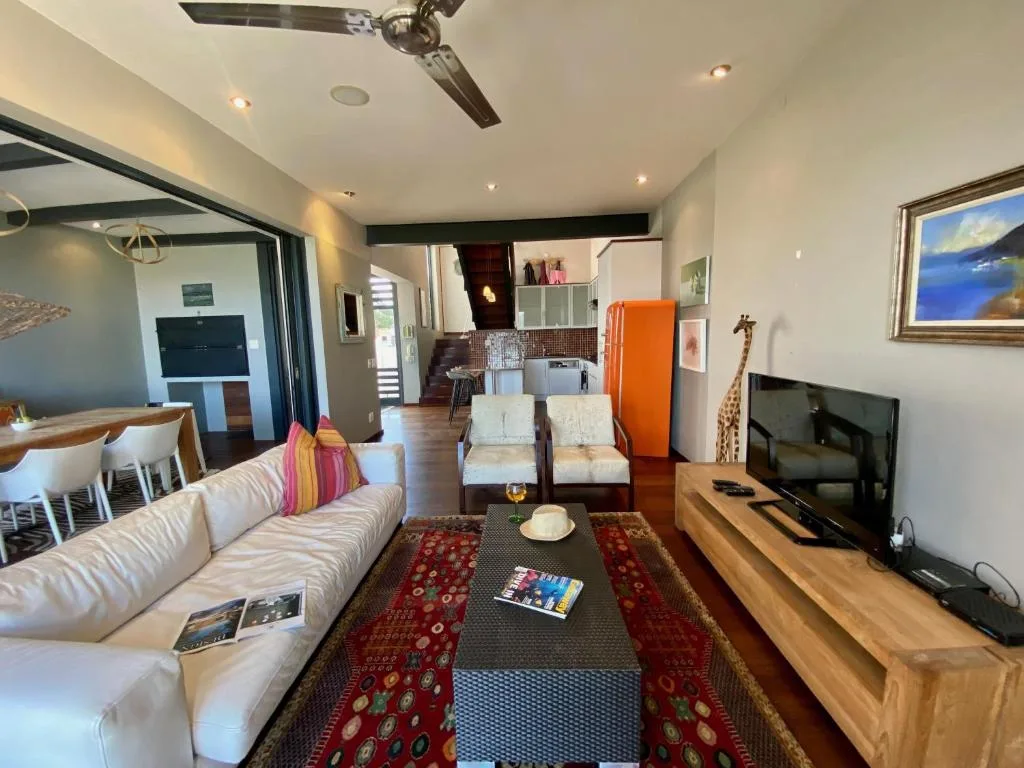 Open-plan living room with white sofa, TV, and colorful cushions