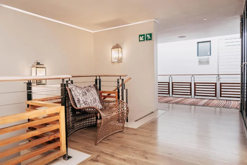 Modern mezzanine deck with wicker seating and wooden railings overlooking waterfront