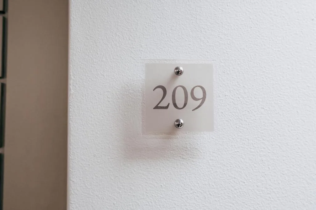 Frosted glass door number plate displaying 209 on white wall