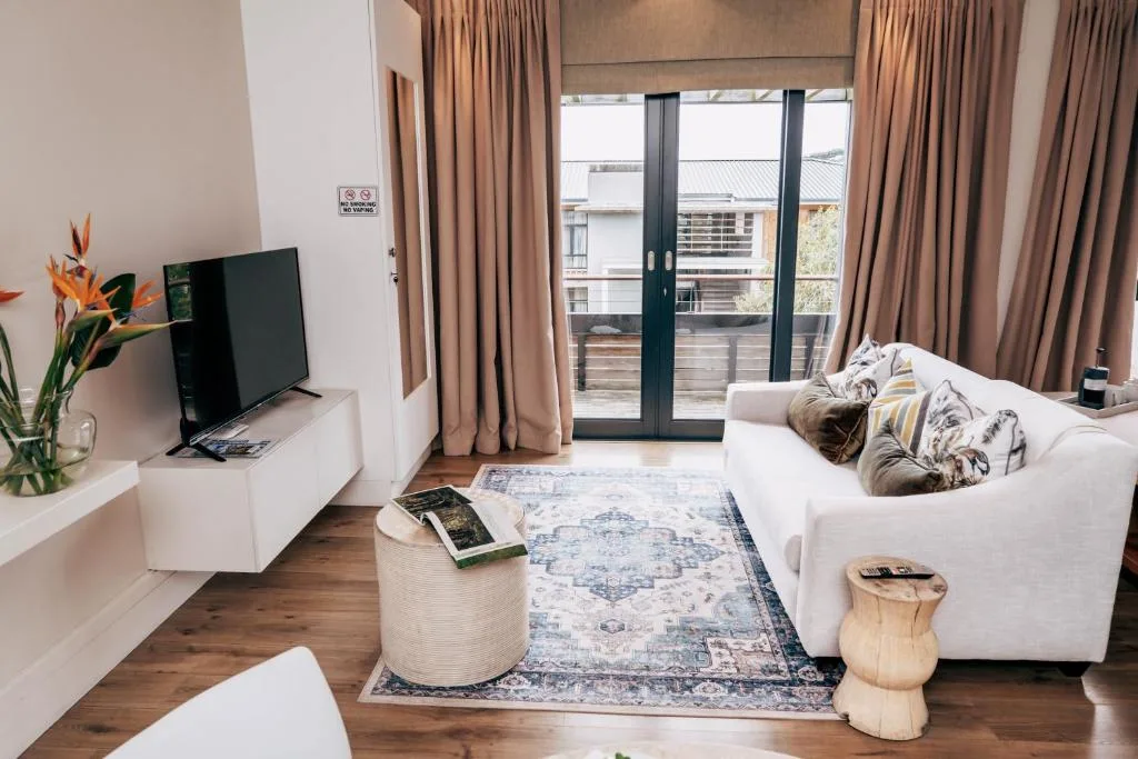 Bright lounge with white sofa, TV, and sliding doors opening to balcony