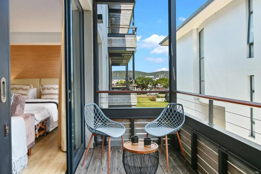 Modern deck with two chairs, small table, mountain and garden views