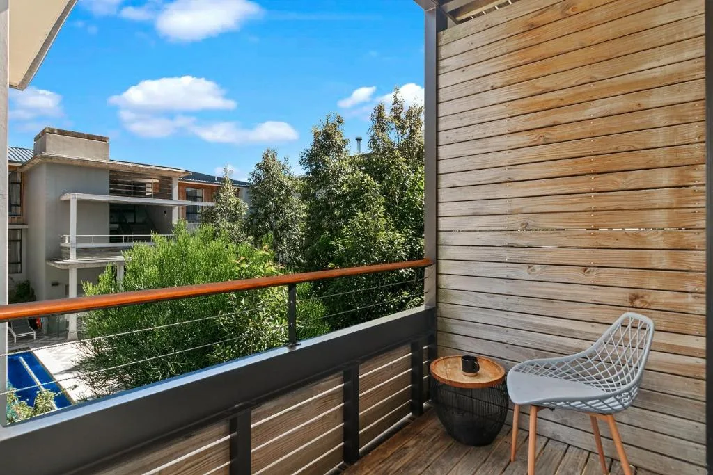 Wooden deck with white chair and side table overlooking green gardens