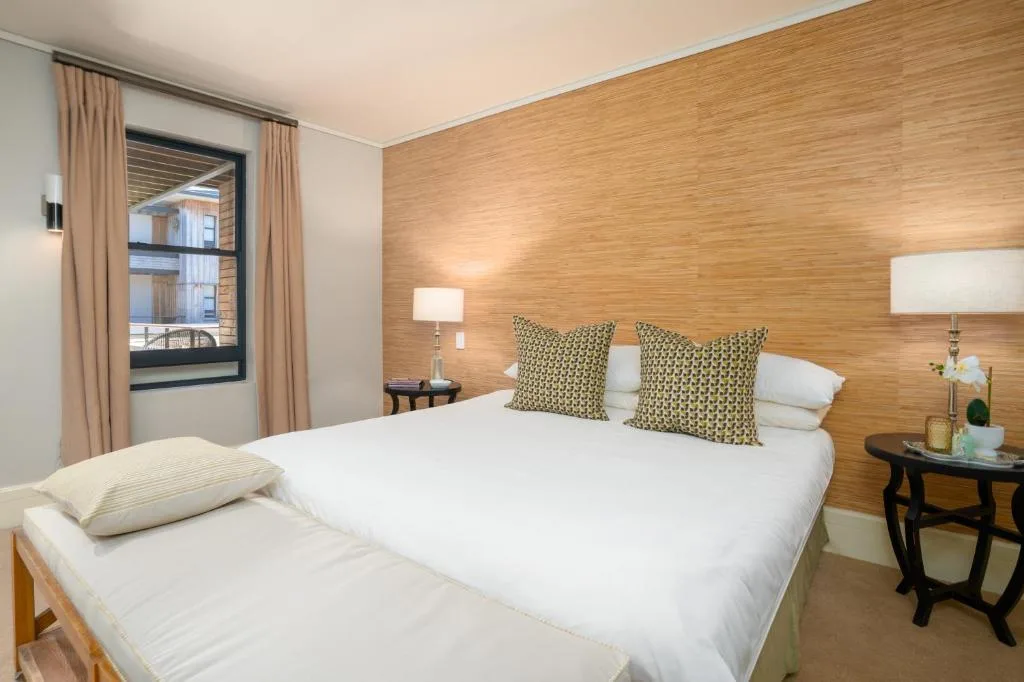 Modern bedroom with queen bed, wooden accent wall, and contemporary lighting fixtures