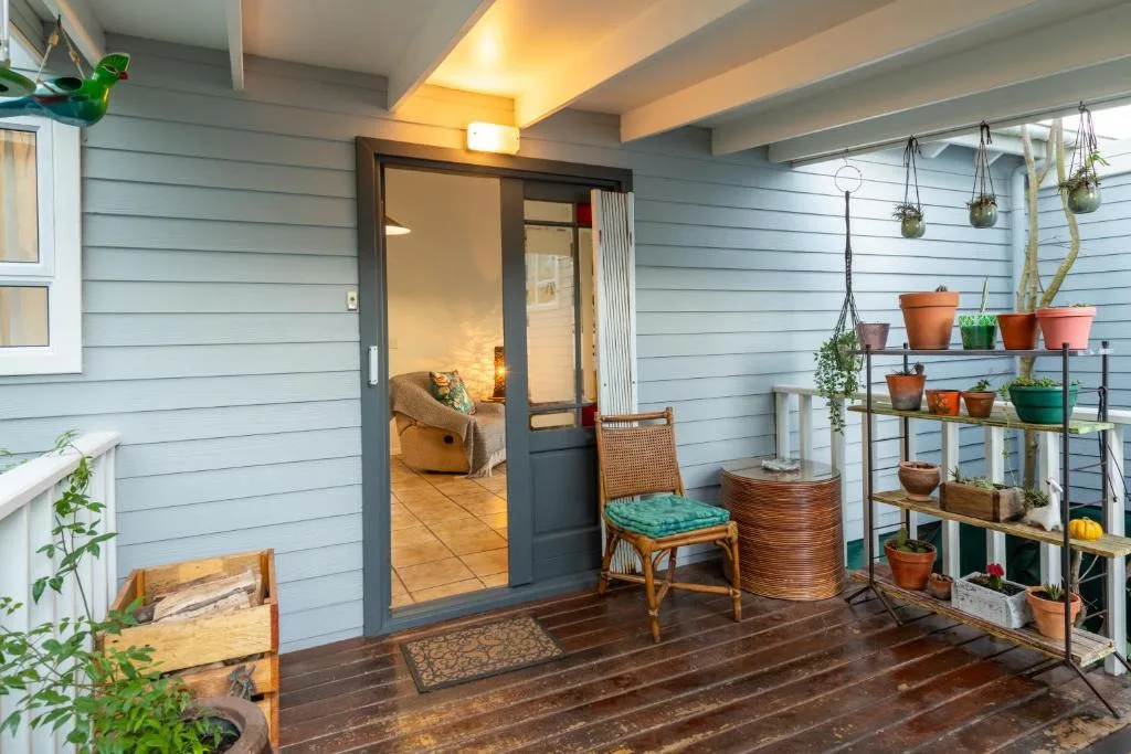 Covered patio with potted plants, wooden chair, and entrance door