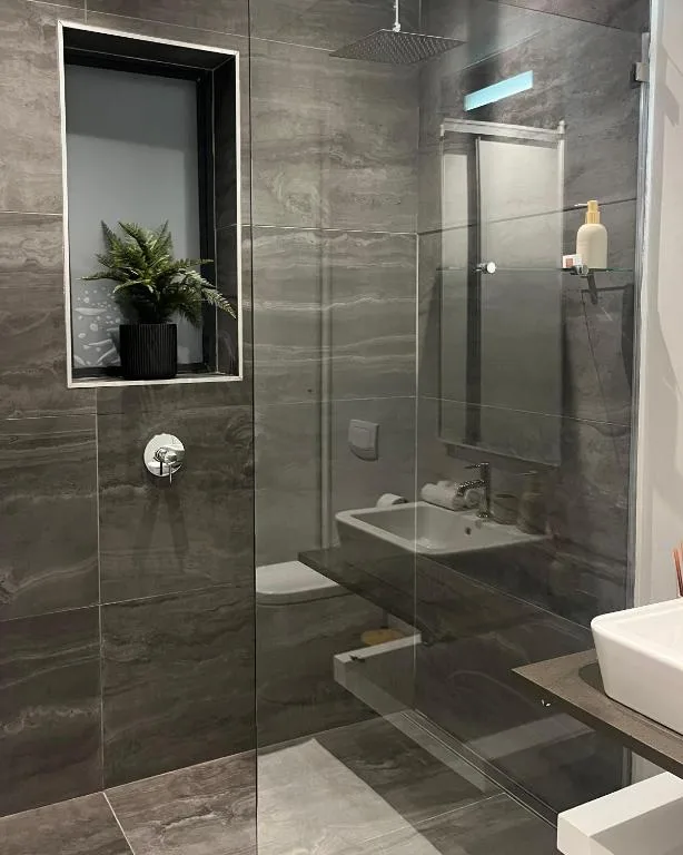 Modern gray tiled bathroom with glass shower enclosure and vanity sink