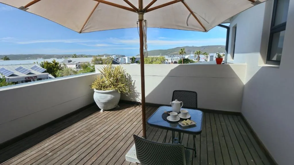Rooftop deck with umbrella, seating, and panoramic lagoon views