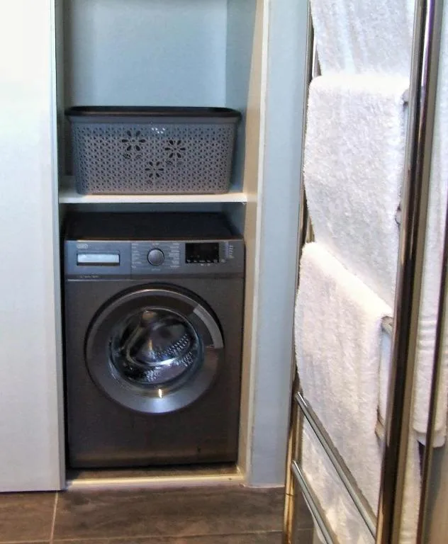 Modern washing machine in built-in laundry nook with storage shelves
