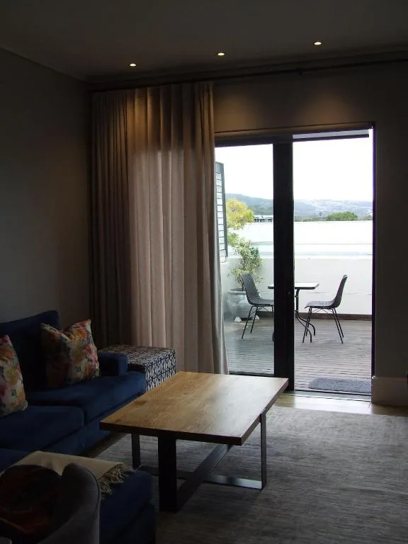 Modern lounge with blue sofa overlooking lagoon and mountains through glass doors