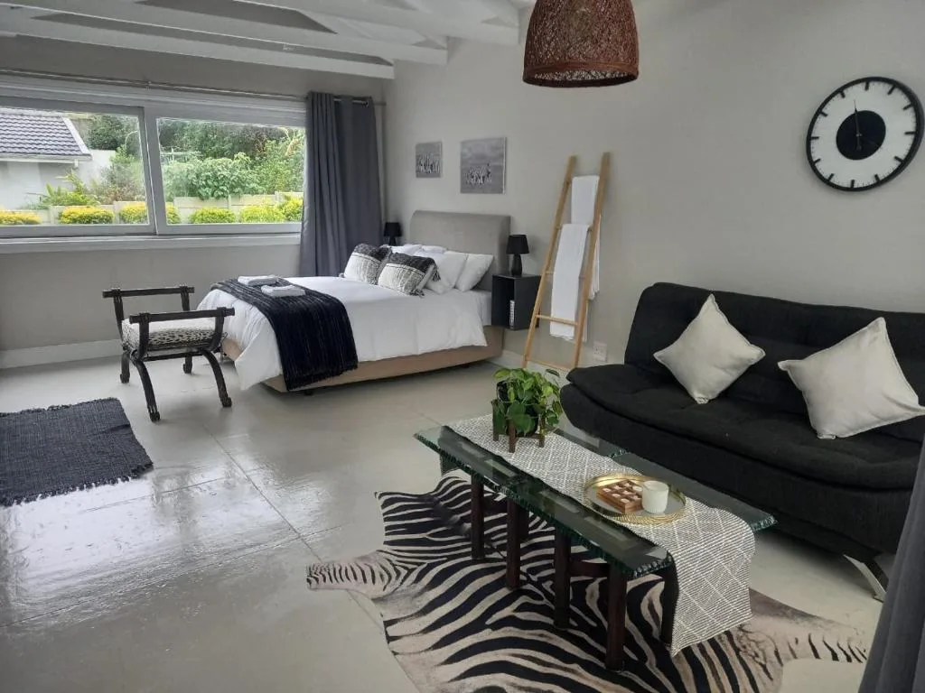 Modern bedroom with queen bed, black sofa, garden views through windows