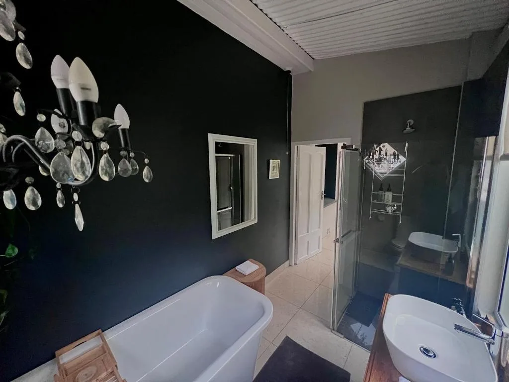 Modern bathroom with freestanding bathtub, vanity, and dark accent wall