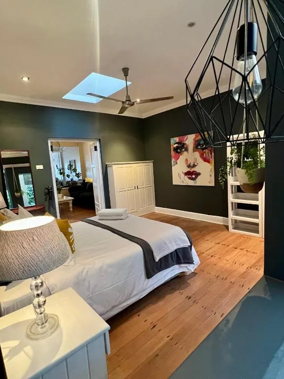 Spacious bedroom with queen bed, skylight, dark green walls, and modern artwork