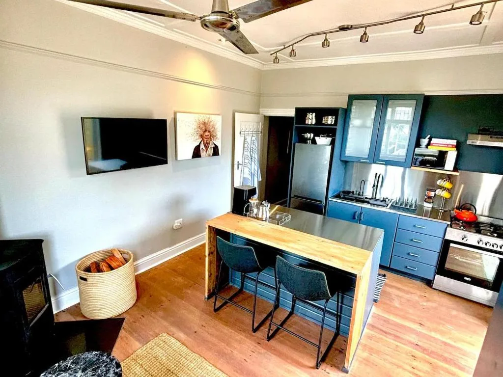 Modern kitchen with blue cabinetry, stainless steel appliances, and wooden island counter
