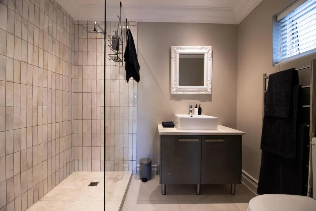 Modern bathroom with walk-in shower, vessel sink, and illuminated mirror