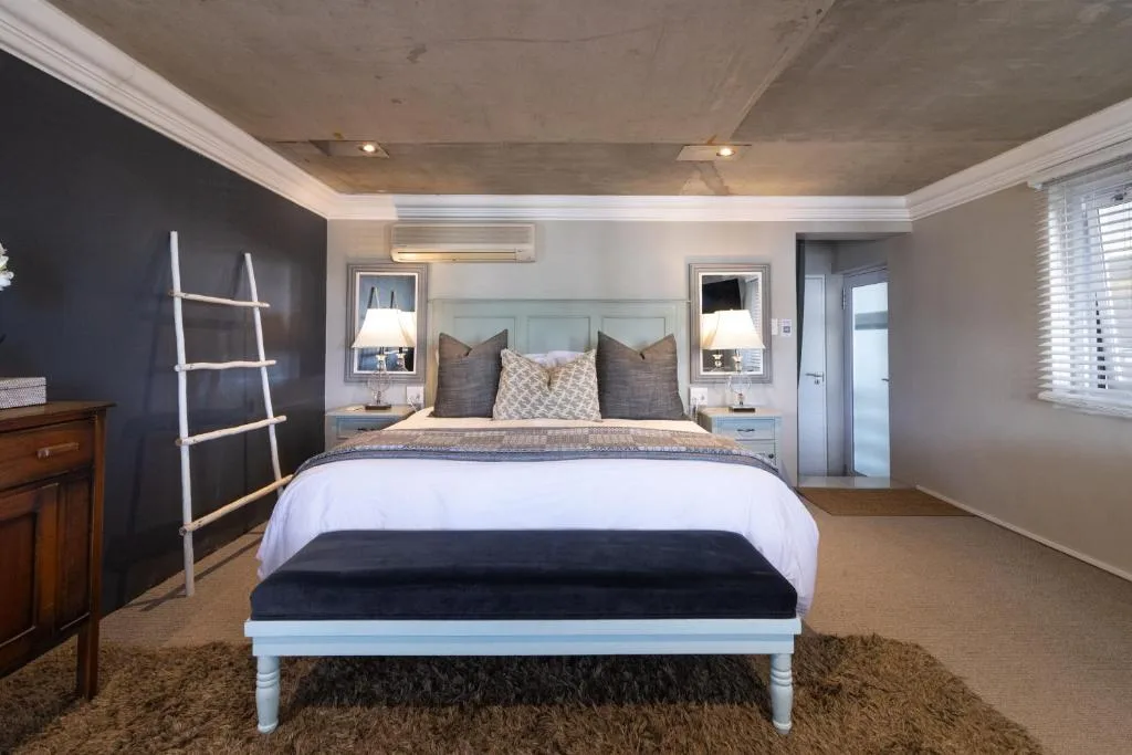 Spacious modern bedroom with queen bed, dark accent wall, and ensuite access