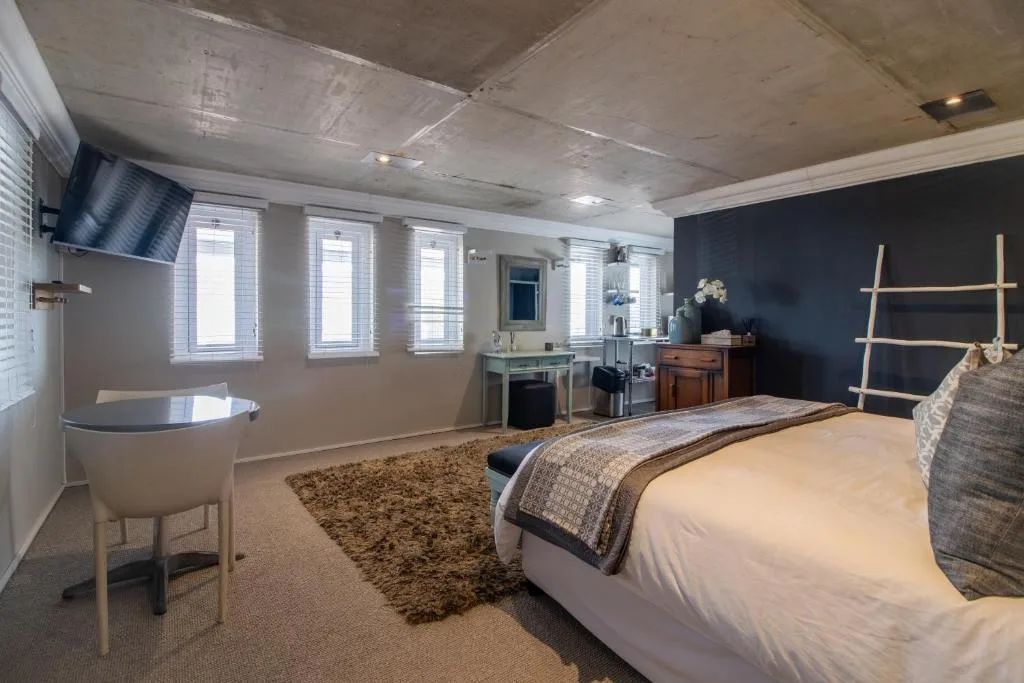 Modern bedroom with queen bed, TV, vanity, and dark feature wall