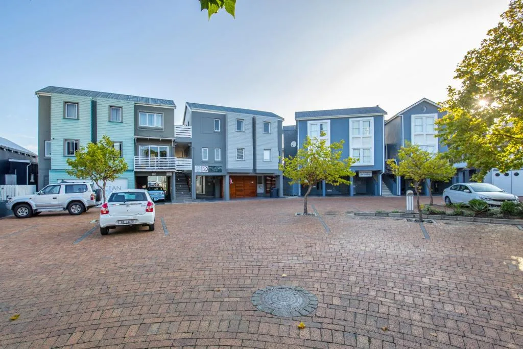 Row of colorful modern townhouses with parking area and landscaping