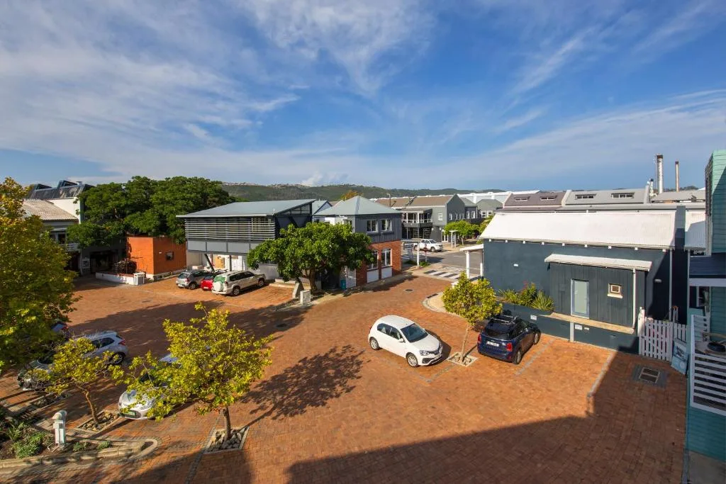 Aerial view of modern apartment complex with parked cars and lagoon beyond