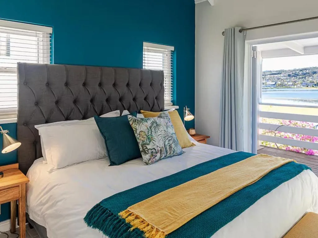 Stylish bedroom with teal walls, tufted headboard, and lagoon view