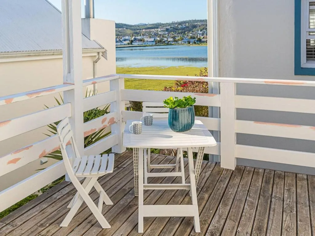Wooden deck with white furniture overlooking Knysna Lagoon and distant hills