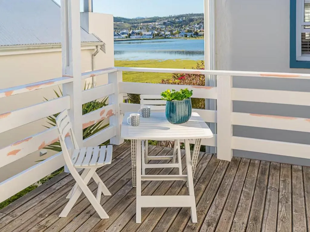 Waterfront deck with white chairs, table, and lagoon view beyond