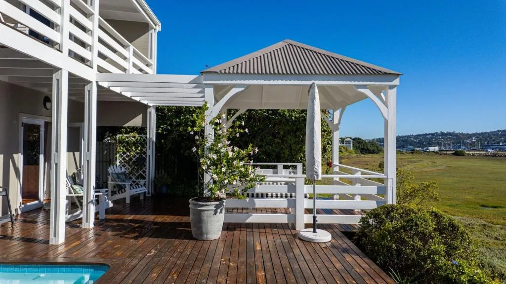 Spacious wooden deck with white pergolas, shade structures, and garden views